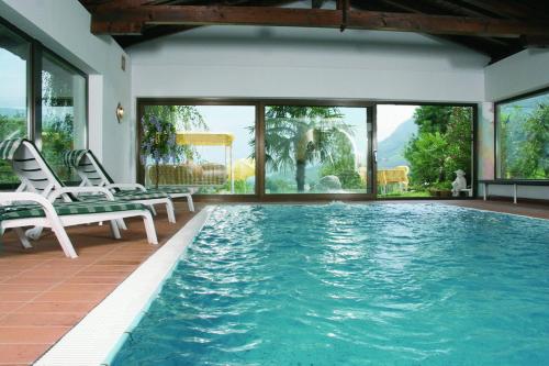 a large swimming pool with two chairs and a table at Hotel Laurin in Lagundo