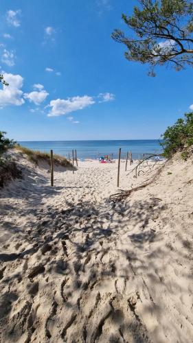 une plage de sable avec une clôture en bois dans le sable dans l'établissement Posesja Kapitańska Przy Plaży Apartments Grzybowo by Noclegi Renters, à Grzybowo