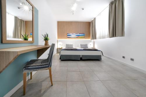 a bedroom with a bed and a desk and a chair at Morasol Suites in Puerto Rico de Gran Canaria