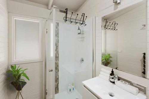 a white bathroom with a shower and a sink at AALFOR LODGE - Luxury Cabin with Spa & Cinema! in Mount Buller