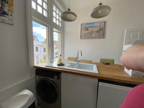 a kitchen with a sink and a washing machine at Spacious 3BR, town centre, 8 min walk to beach in Bournemouth