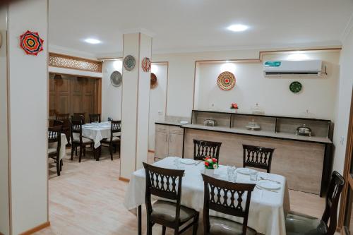 a dining room with tables and chairs and a kitchen at Oasis Boutique in Bukhara