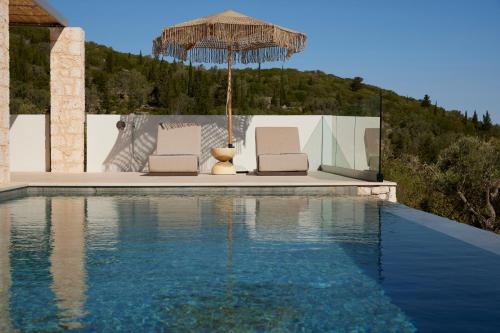 two chairs and an umbrella next to a swimming pool at Epiphany Villas Lefkada in Tsoukaladhes
