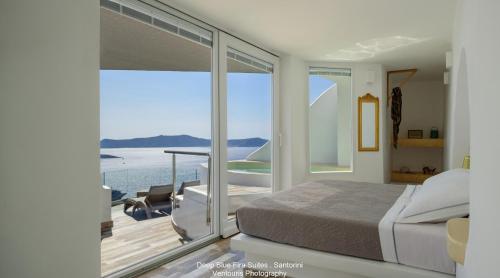 a bedroom with a bed and a view of the ocean at Fira Deep Blue Suites in Fira