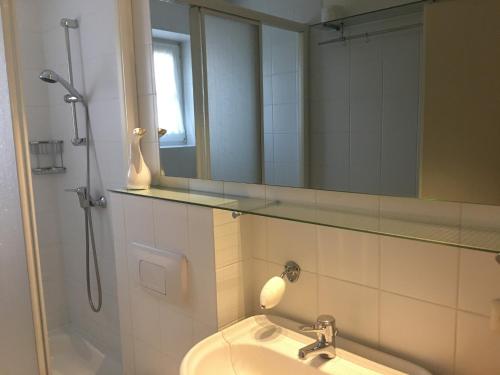 a bathroom with a sink and a mirror and a shower at Ferienwohnung "Zum Böhler Leuchtturm" in Sankt Peter-Ording