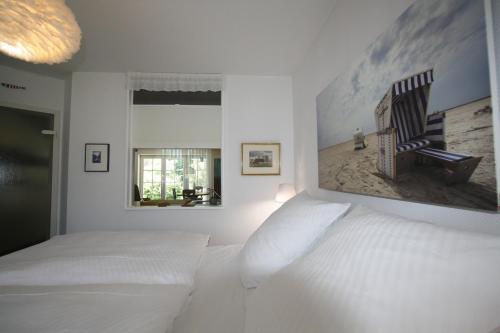 a white bedroom with a bed and a picture on the wall at Ferienwohnung "Zum Böhler Leuchtturm" in Sankt Peter-Ording
