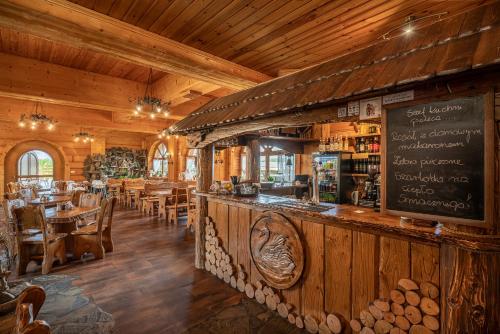 a restaurant with a bar and tables and chairs at Łabędź Hotel Karczma in Iława