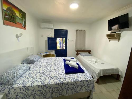 a bedroom with two beds and a tv on the wall at Pousada Chez Julie in Pontal do Peba