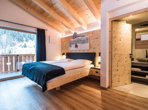 a bedroom with a large bed and a large window at Apartments Piciulei in Selva di Val Gardena