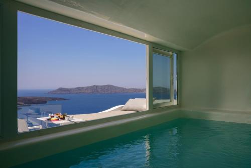 a room with a swimming pool and a large window at Fira Deep Blue Suites in Fira