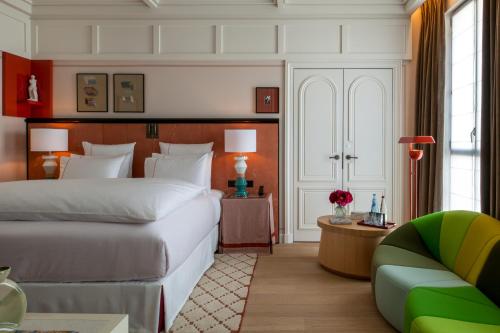 a bedroom with a large white bed and a couch at Sinner Paris in Paris
