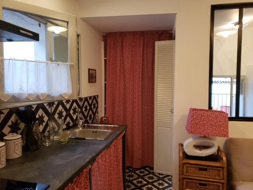 a kitchen with a sink and a red curtain at le balcon in Camps-sur-lʼAgly