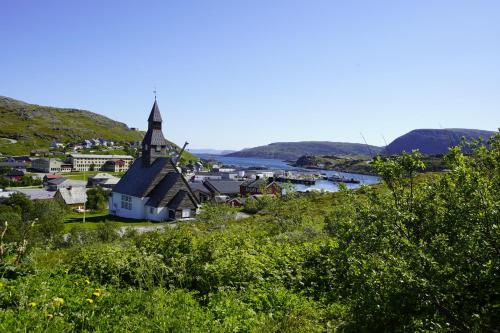 a small town with a church and a river at Havøysund house with a beautiful view in Måsøy
