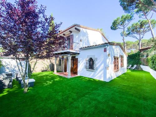 a white house with a yard with green grass at Villa en el Golf Costa Brava a 5 min de la playa in Santa Cristina d'Aro