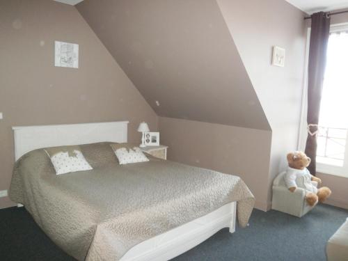 a bedroom with a bed and a teddy bear in a chair at Aux Fontaines Honfleur in Honfleur