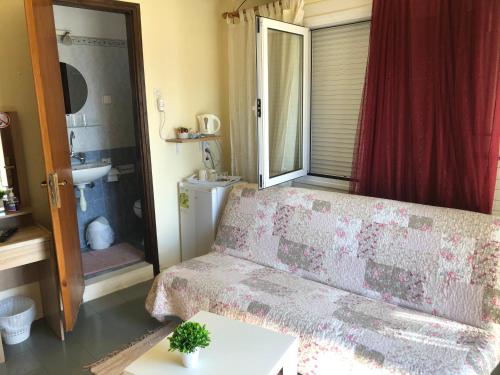 uma sala de estar com um sofá e uma janela em Platanos Rooms em Agia Marina