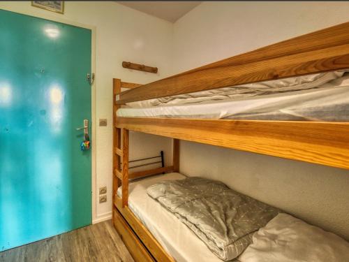 Cette chambre dispose de lits superposés avec 2 lits superposés et une porte. dans l'établissement Appartement cosy 4-5 pers. skis aux pieds à Morillon 1100 - FR-1-642-31, à Morillon