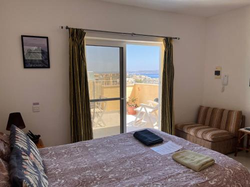 um quarto com uma cama e vista para uma varanda em All Nations Holiday Home em Għajnsielem