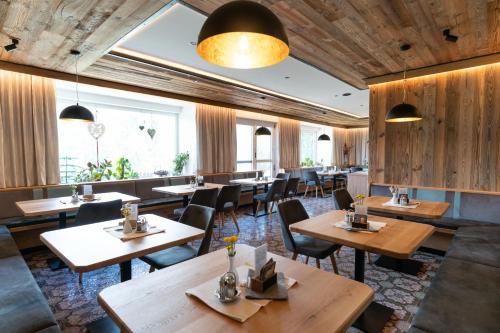 un restaurante con mesas y sillas de madera en Sonnenhügel, en Ramsau am Dachstein