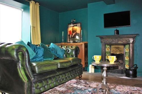 a living room with a leather couch and a fireplace at The Wolf's Den in Patrington