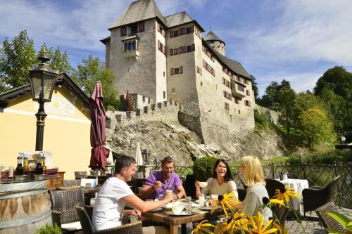 a group of people sitting at a table in front of a castle at INN-Studio Ursula in Brixlegg