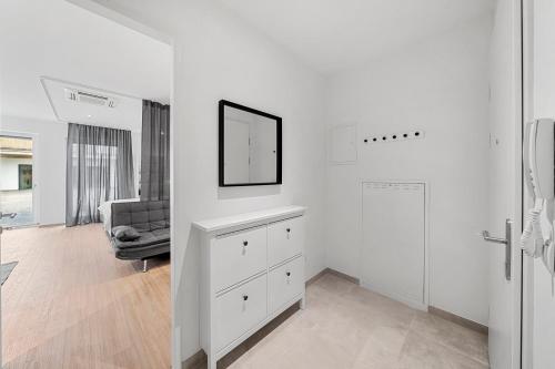a white living room with a dresser and a chair at VibeStudio 304 - Central - AC - Licensed - Parking Nearby in Vienna