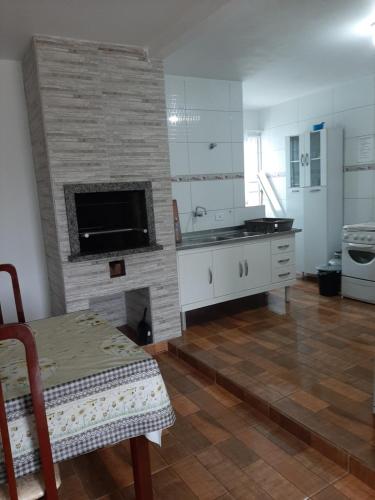 a kitchen with a stone fireplace with a table and a table sidx sidx at Casa em Matinhos PR in Matinhos