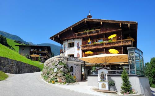 un grand bâtiment avec un parasol devant lui dans l'établissement Hotel Kirchbichlhof, à Hippach