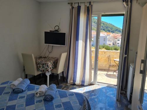 a bedroom with a bed and a tv and a window at Rooms Anđelka in Bol