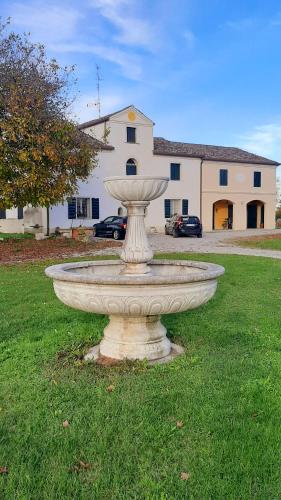 a large stone fountain in the grass in front of a house at Casa del sole in Rivarotta