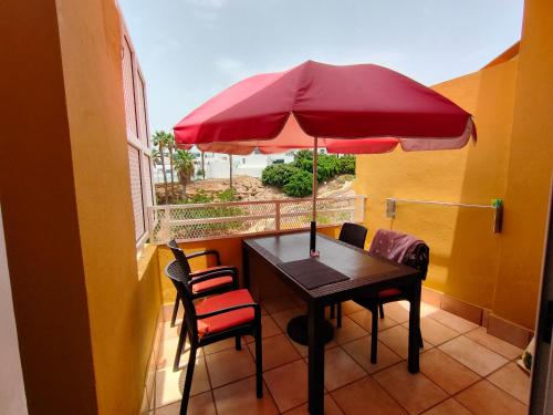a table and chairs with a red umbrella on a balcony at LUX Orlando in Adeje