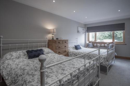 a bedroom with two beds and a dresser and a window at Bayview House - 4 Bedroom Luxurious Holiday Home - Saundersfoot in Saundersfoot