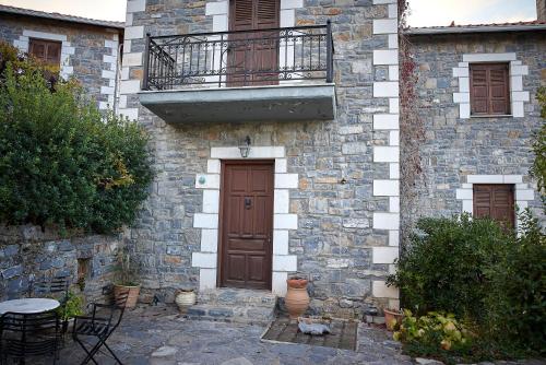 a stone building with a wooden door and a balcony at Malevos Traditional Houses in Áyios Pétros
