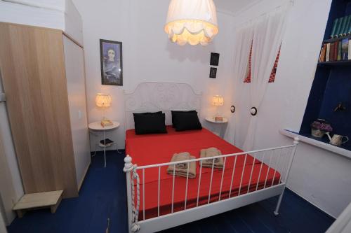 a bedroom with a red bed with two tables and a chandelier at Dandy Villas Velanidia Sailor's House - Private Maisonette - Sea View in Velanídhia