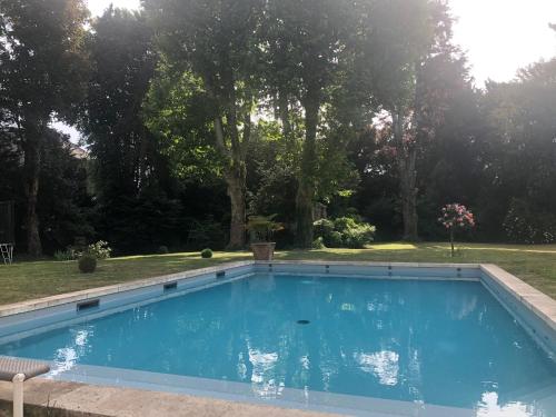 una piscina azul en un patio con árboles en La Grande Carrée en Saint-Cyr-sur-Loire