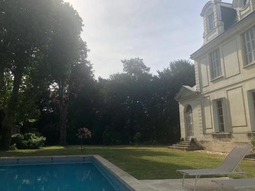 una casa con piscina frente a una casa en La Grande Carrée, en Saint-Cyr-sur-Loire