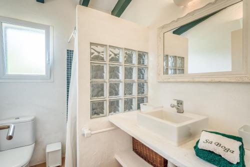 uma casa de banho branca com um lavatório e um espelho em Sa Boga em Cap d'en Font