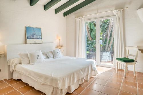 a bedroom with a white bed and a large window at Sa Boga in Cap d'en Font