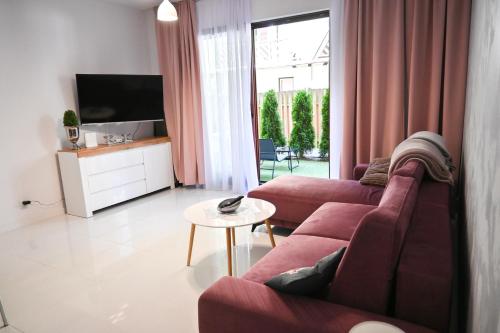 a living room with a red couch and a tv at Apartamenty Morskie Moonlight Łukęcin in Łukęcin