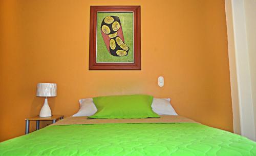 a bedroom with a green bed with a picture on the wall at North Star Hostal Guayaquil in Guayaquil