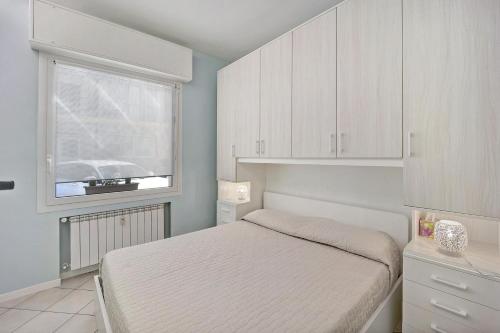 a white bedroom with a bed and a window at Serendipity in Alassio