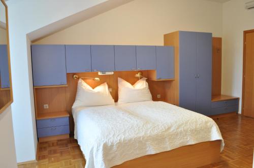 a bedroom with a large white bed with blue cabinets at Seehotel Herlinde in Podersdorf am See