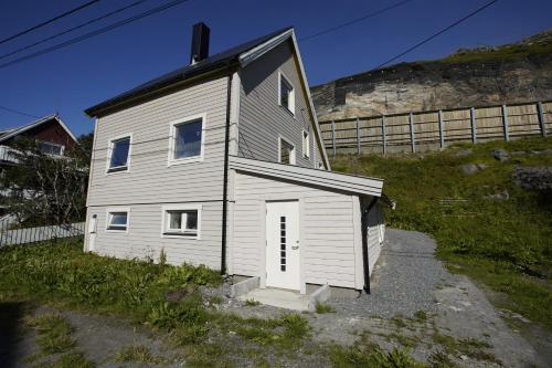 een klein huis met een witte deur op een heuvel bij Small cozy apartment by the sea in Havøysund