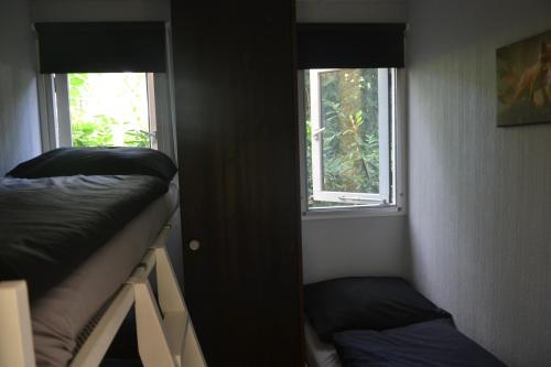 a room with two bunk beds and two windows at VH Wellness Natuurhuisje Het spikkennust in Diever