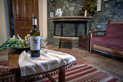 a bottle of wine sitting on a table with a glass at Malevos Traditional Houses in Áyios Pétros