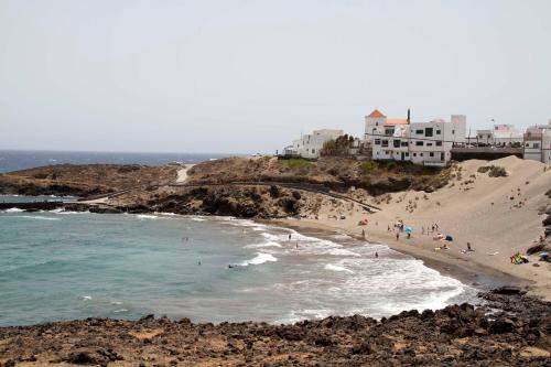 a group of people on a beach next to the ocean at Navy Apartment, El Poris in Arico