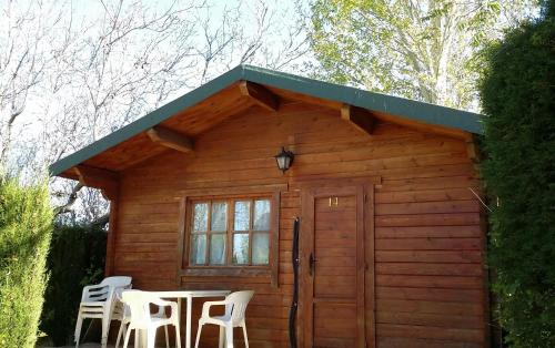 a small wooden cabin with two chairs and a table at Camping Ruta del Purche in Monachil