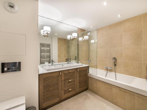 une salle de bain avec un lavabo, une baignoire et un miroir dans l'établissement Appartement élégant avec accès direct aux pistes et espace bien-être - FR-1-565-14, à Les Allues