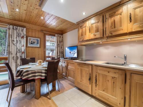 une cuisine avec des placards en bois, une table et une télévision dans l'établissement Appartement Fonctionnel, 4 Pers avec Garage et Terrasse à 100m des Pistes à Méribel - FR-1-565-15, à Les Allues
