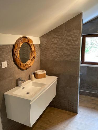 La salle de bains est pourvue d'un lavabo blanc et d'un miroir. dans l'établissement CHALET-MICHEL avec SPA, à Montperreux